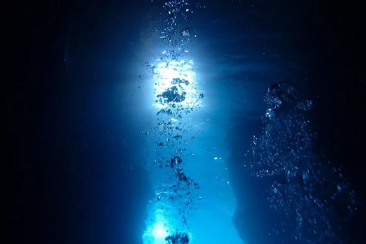 Luftblasen, die in einer tiefblauen Unterwasserumgebung zur Oberfläche aufsteigen