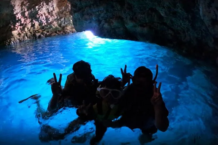 Gruppe von Menschen beim Schnorcheln im leuchtend blauen Wasser einer Grotte