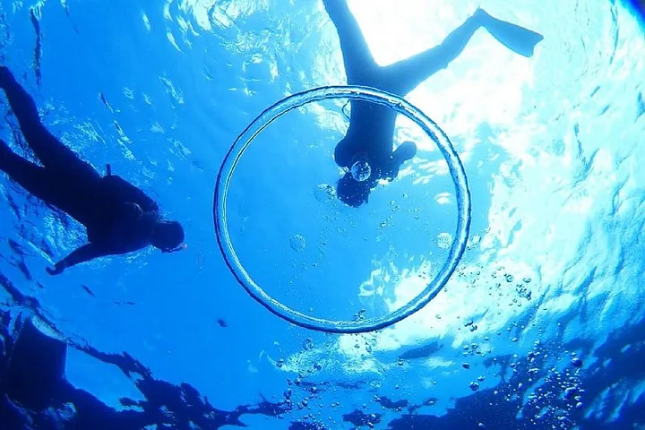 Zwei Menschen beim Schnorcheln unter Wasser, gesehen durch einen Blasenring